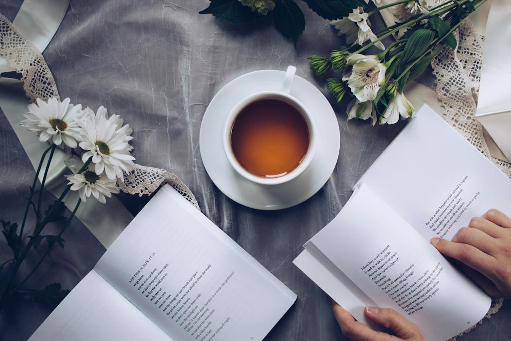 White Ceramic Teacup With Saucer Near Two Books Above Gray Floral Textile